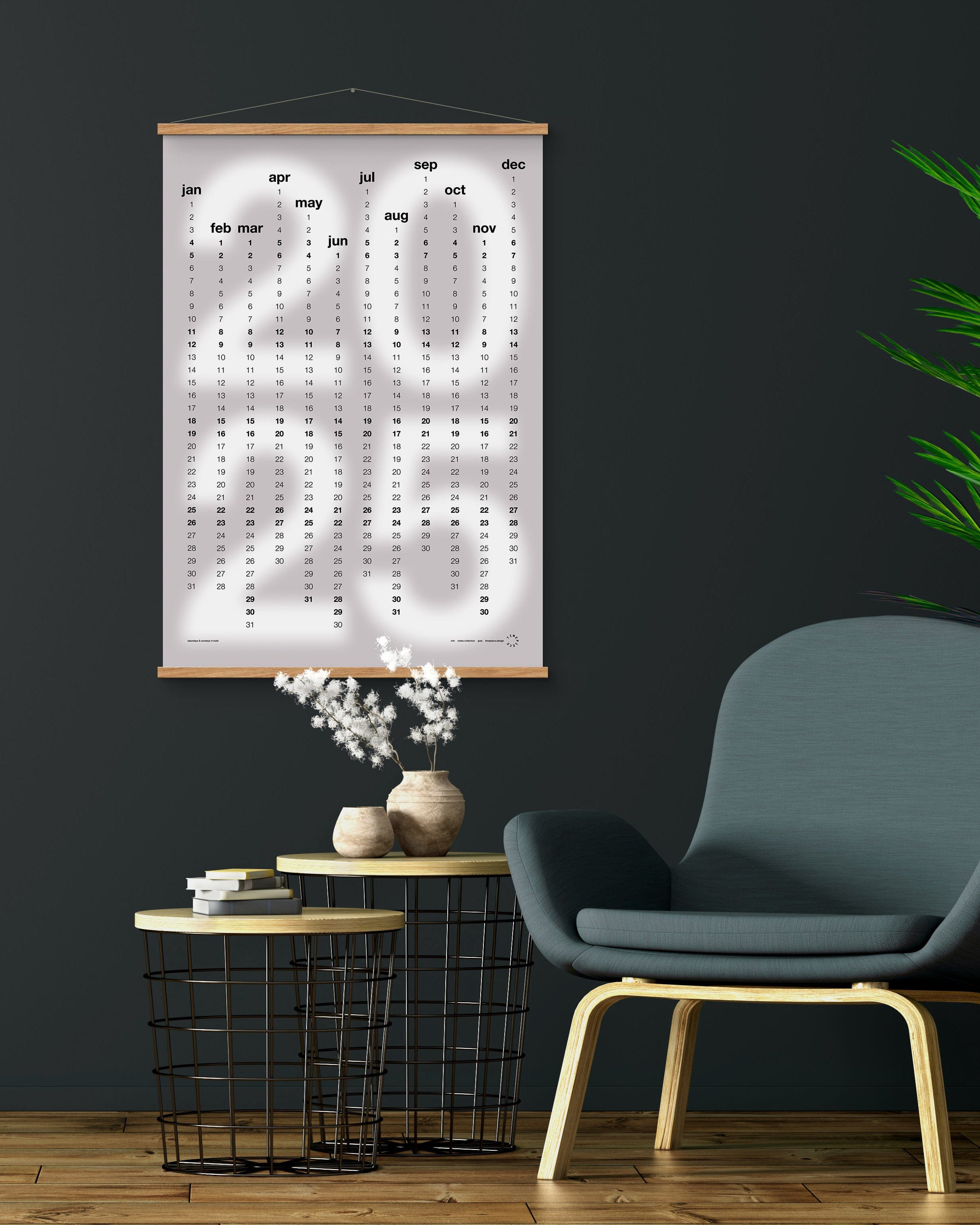 Calendar on a dark wall with a modern chair and decorative items below.