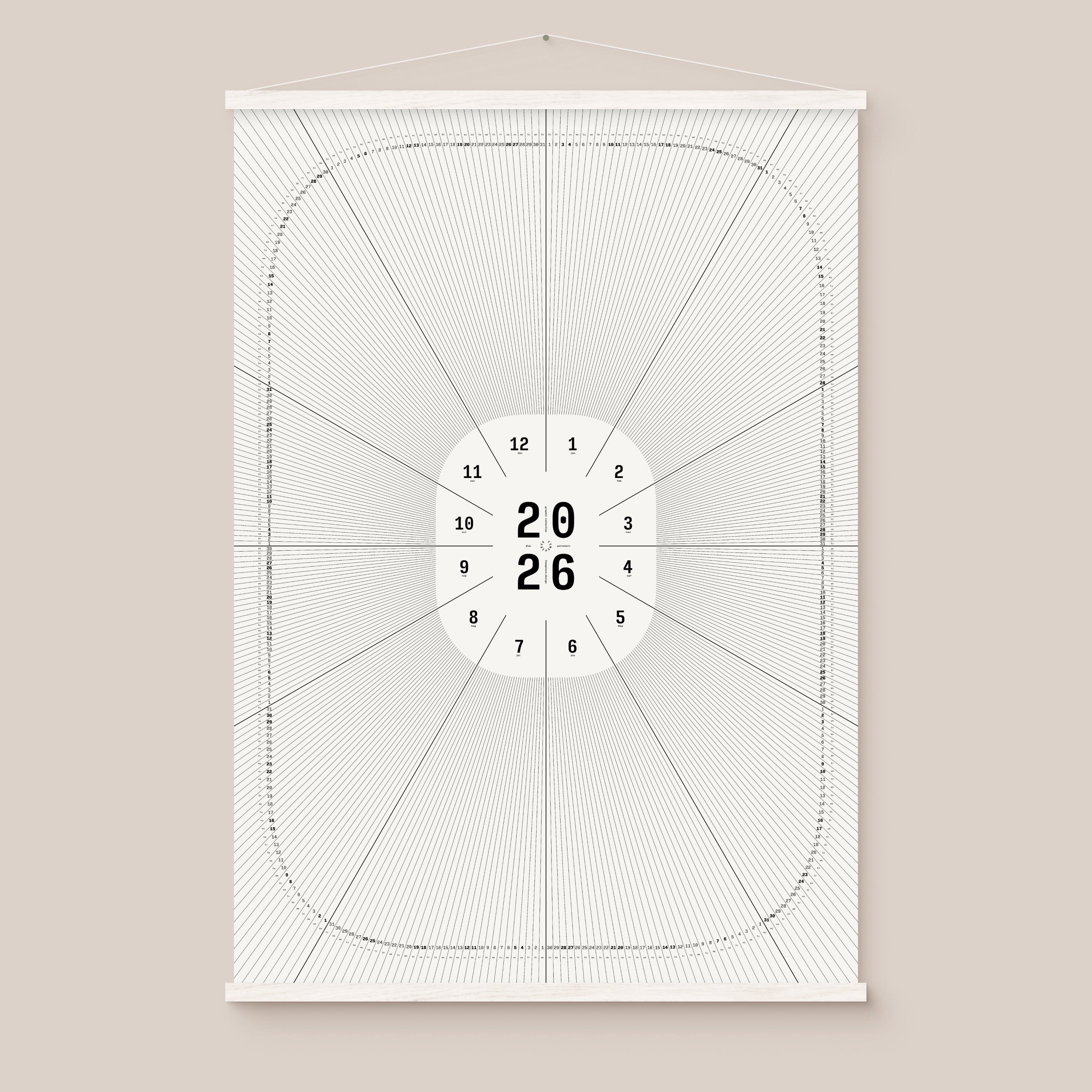 Framed geometric calendar with a circular design and numbers on a beige wall, white hanger frame