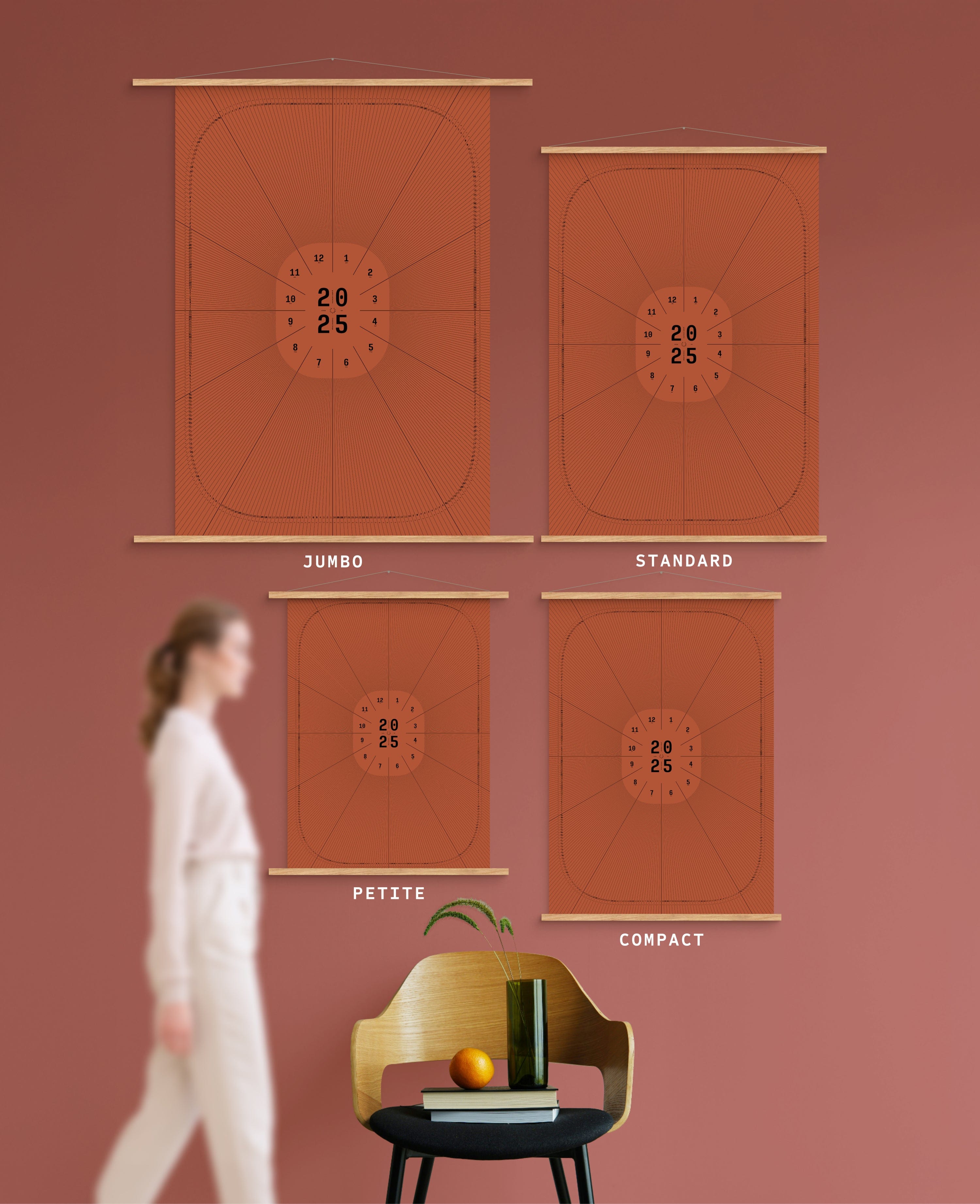 4 sizes of Dial in Red earth colour calendar on terracotta wall, with person, chair, orange and vase shown for scale