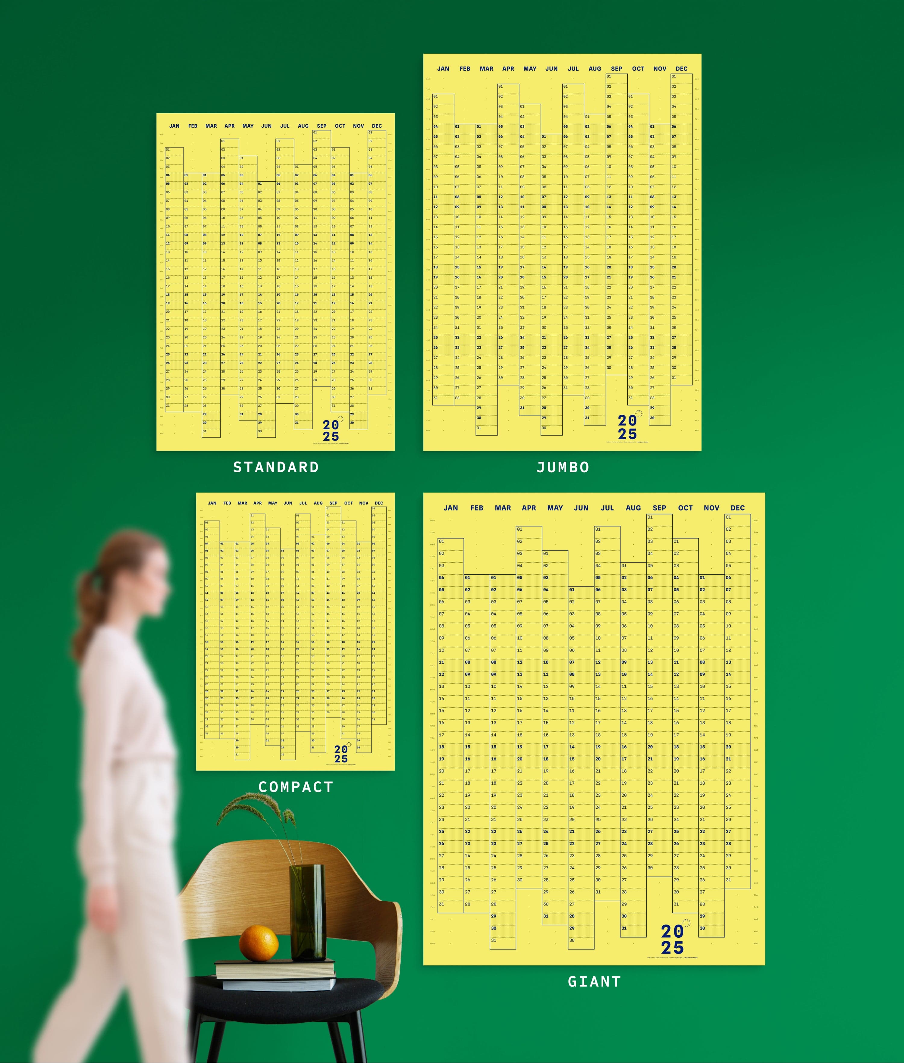 4 sizes of Dotline in Yellow colour yearly planner on green wall, with person, chair, orange and vase shown for scale