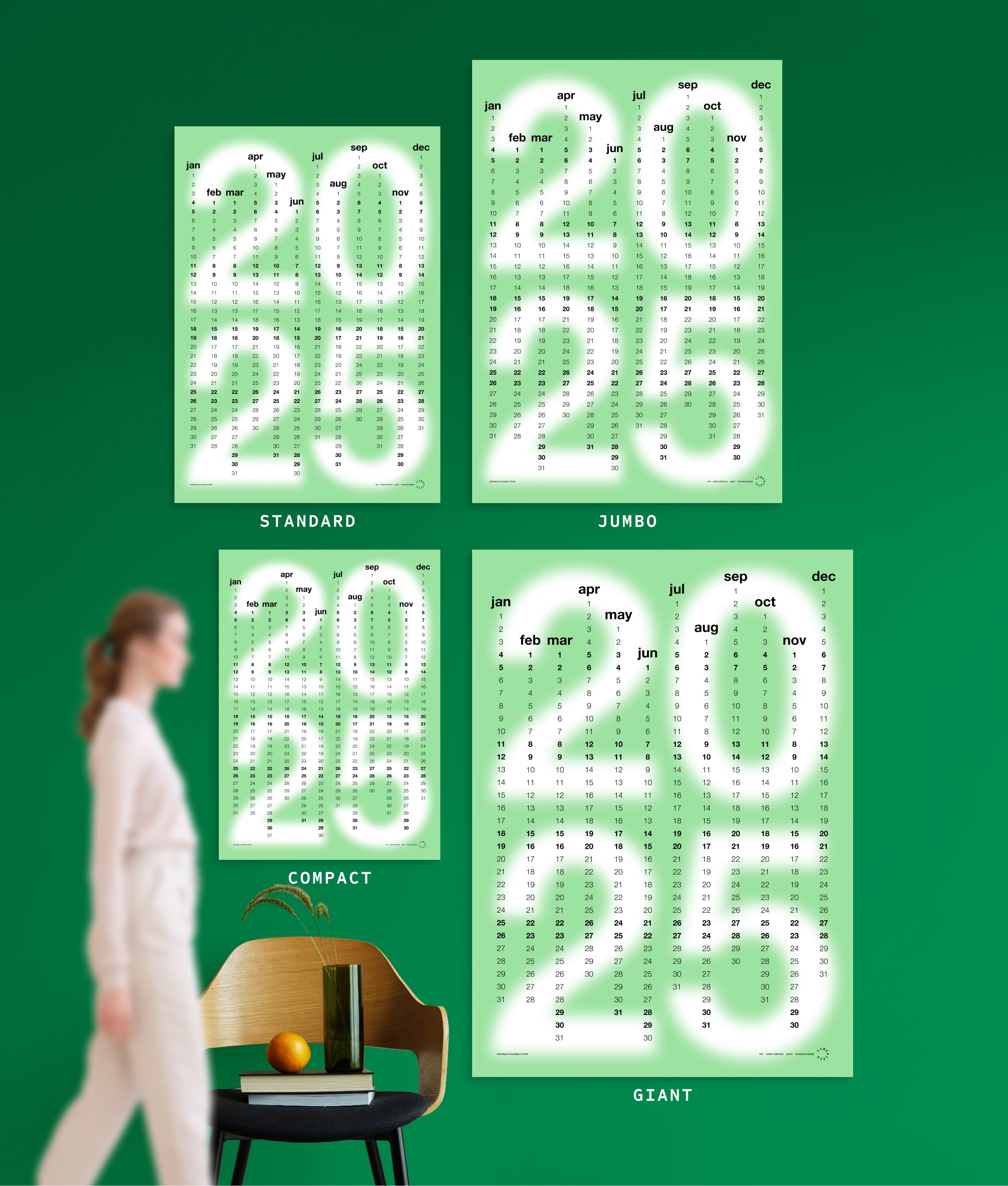 4 sizes of Min in Green colour yearly planner on green wall, with person, chair, orange and vase shown for scale